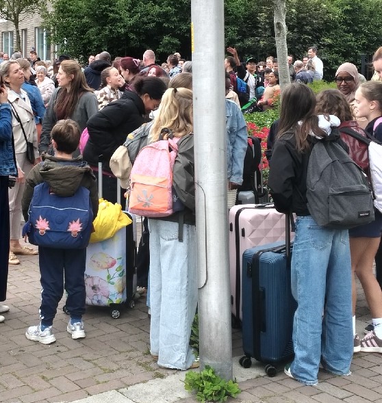 Kinderen wachten met koffers op de bus